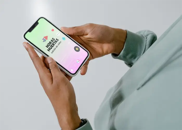 Dos manos de hombre sujetan un móvil en el que se ve una imagen de Tiktok con el lodo de Horas Muertas edición de video